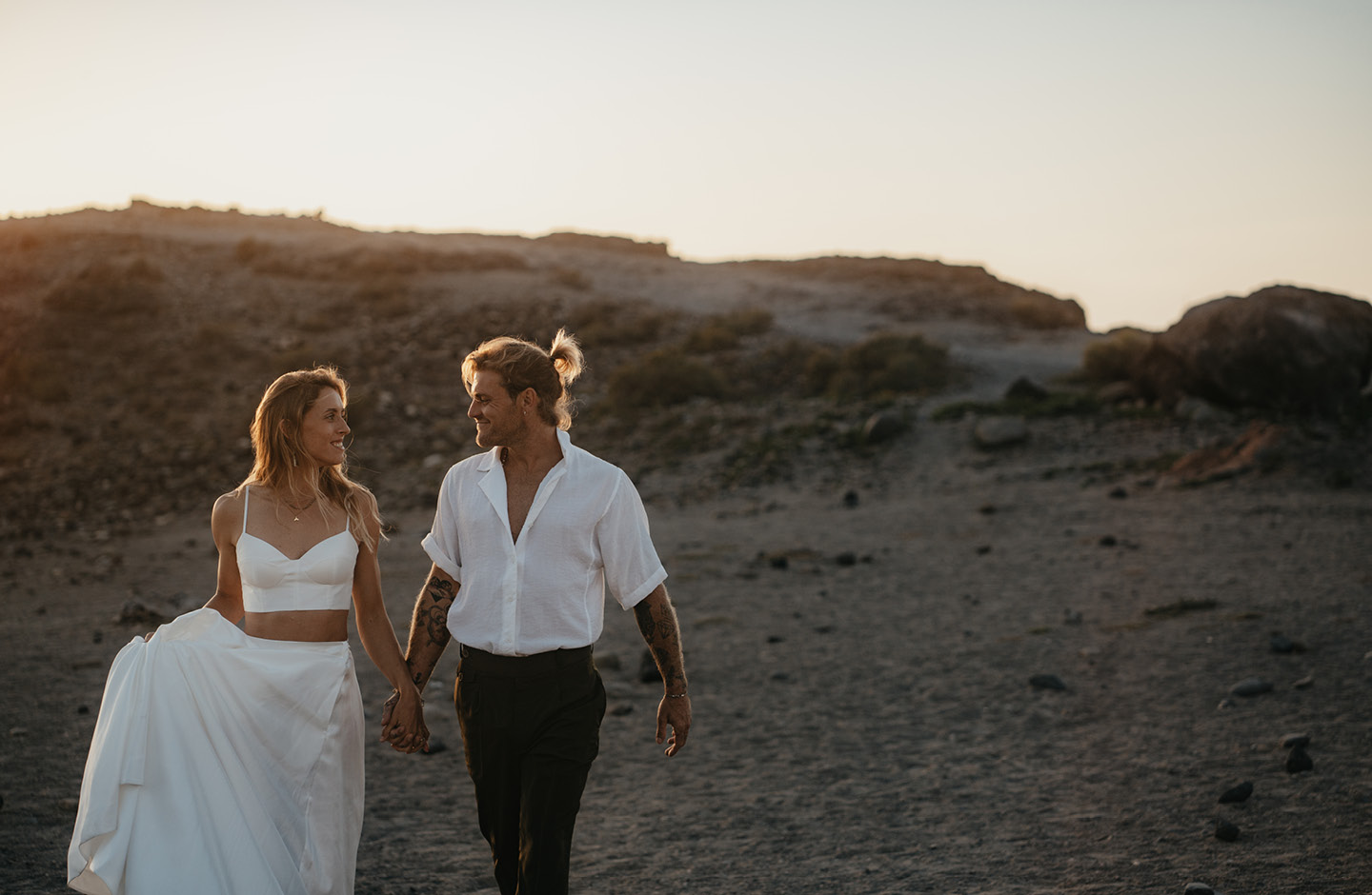 Hochzeitspaar in sommerlichem Outfit Hand in Hand am Strand