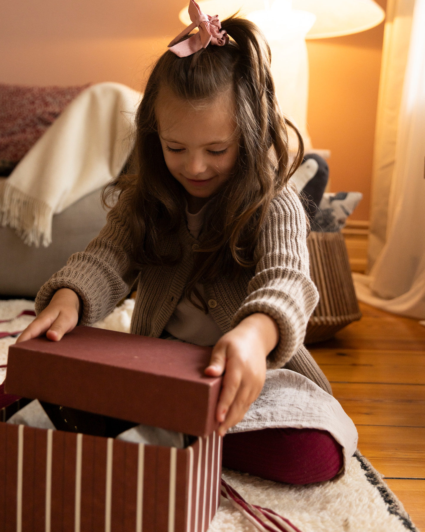 kleines Mädchen öffnet einen Geschenkkarton mit Weihnachtsgeschenk