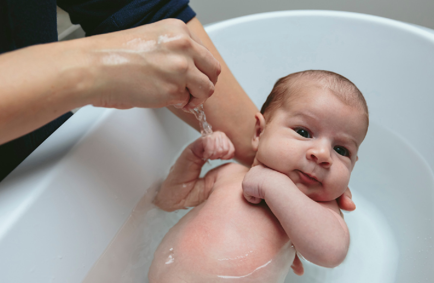 Bildausschnitt von Baby, das von der Mutter in der Wanne gebadet wird