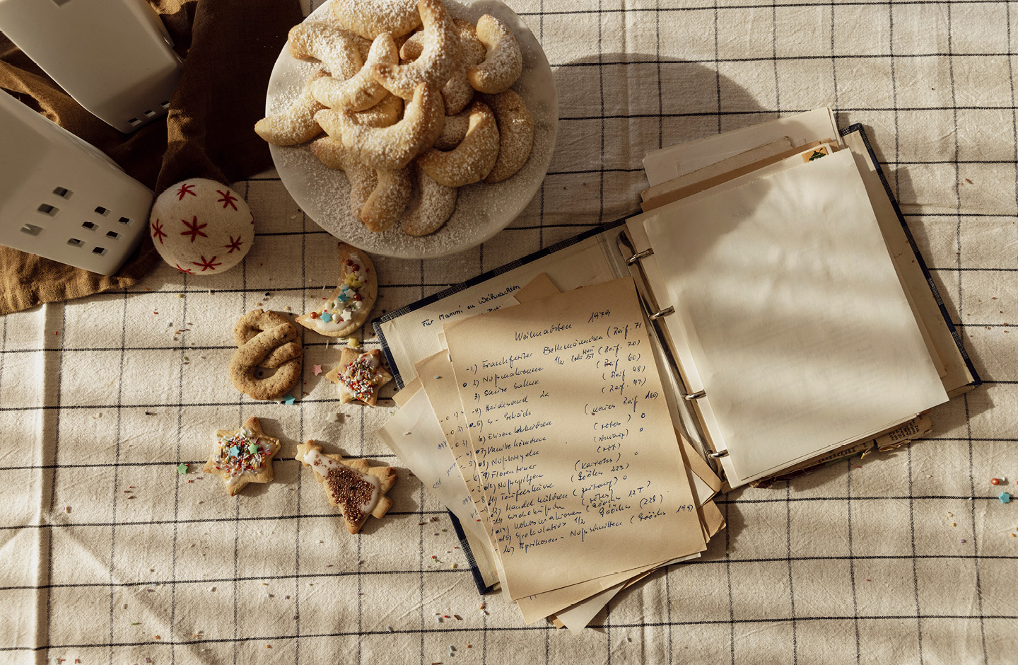 Älteres Rezeptbuch auf einem Tisch mit Deko und frisch gebackenen Plätzchen