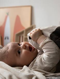 Fröhliches Baby auf einer Kuscheldecke im Wohnzimmer