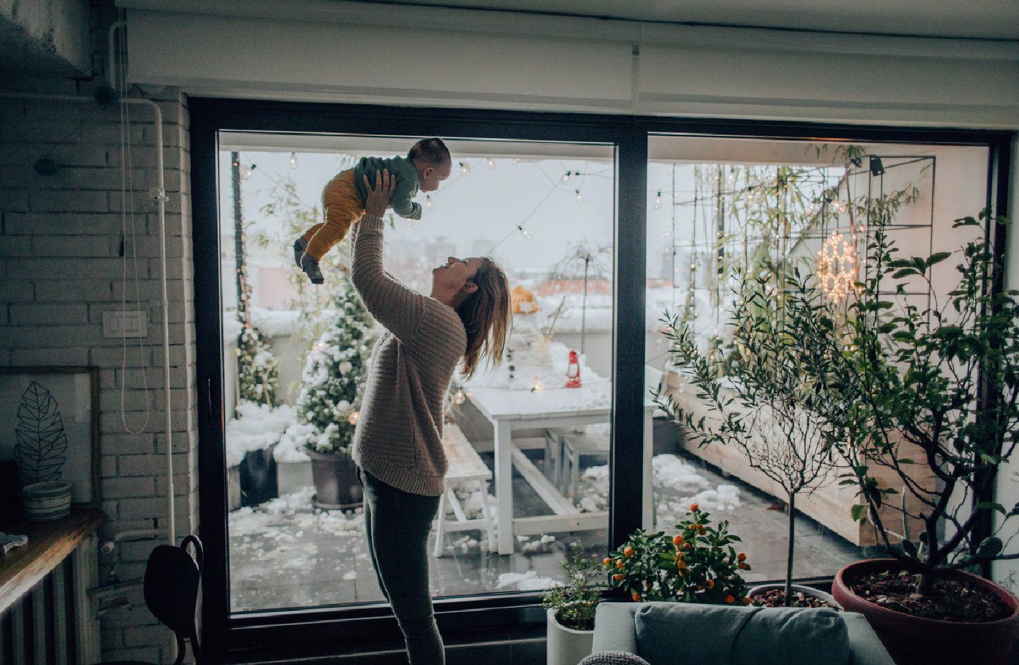 Mutter in weihnachtlich geschmückten Zimmer mit ihrem Baby